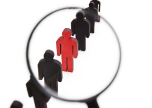 The view through the magnifier on the one wooden red person between other people